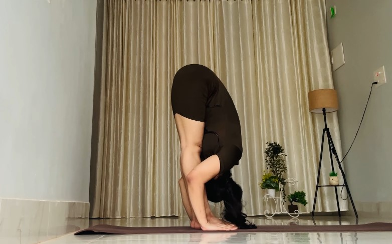 Woman doing Uttanasana yoga pose in her living room
