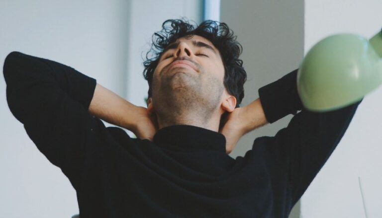 A man relaxes, hands behind his head, in a moment of repose