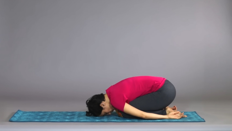 A woman practices Balasana (Child’s Pose) on a yoga mat