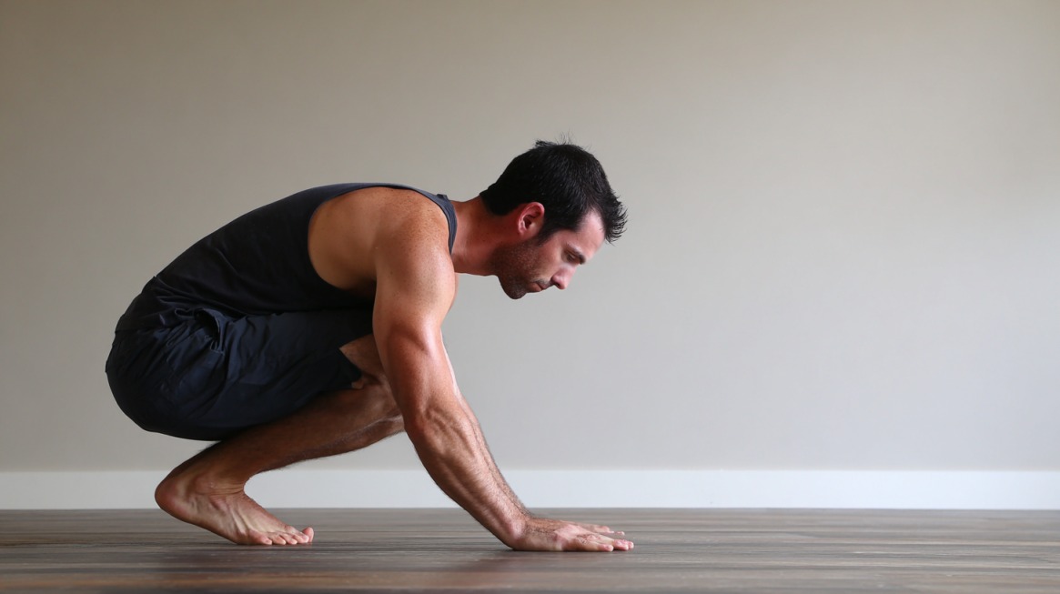 Man preparing for yoga crow pose with hands on the floor