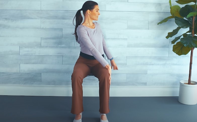 Woman seated, performing a seated spinal stretch
