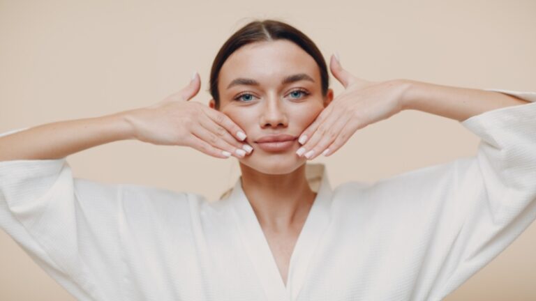 Woman practicing face yoga with her hands placed on her cheeks to tone and lift facial muscles