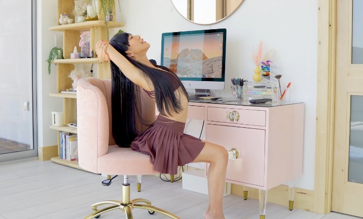 A woman sitting at a desk with her legs propped up, appearing relaxed and engaged in her surroundings