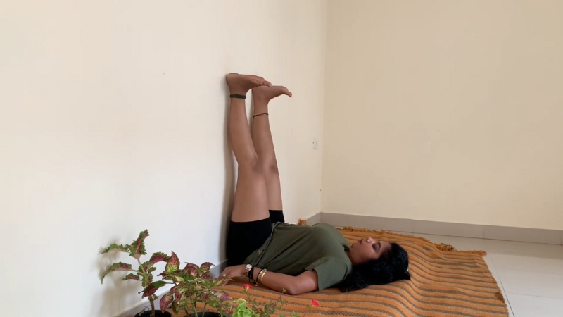 A woman lies on her back with legs resting against the wall in Viparita Karani