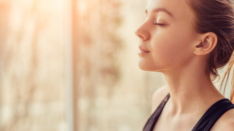 Young woman with closed eyes practicing calm breathing