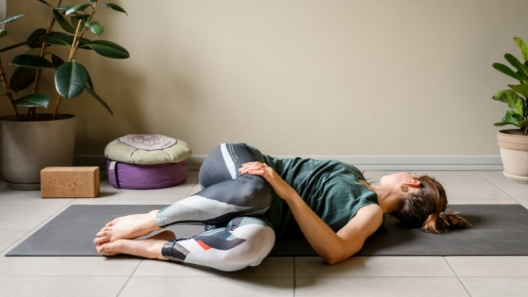 Woman practicing a gentle twist on a yoga mat as part of yoga for digestion